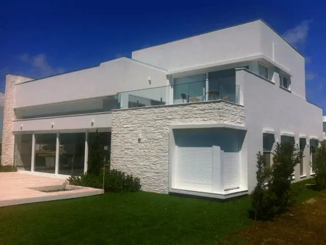 Residência branca com jardim e piso externo
