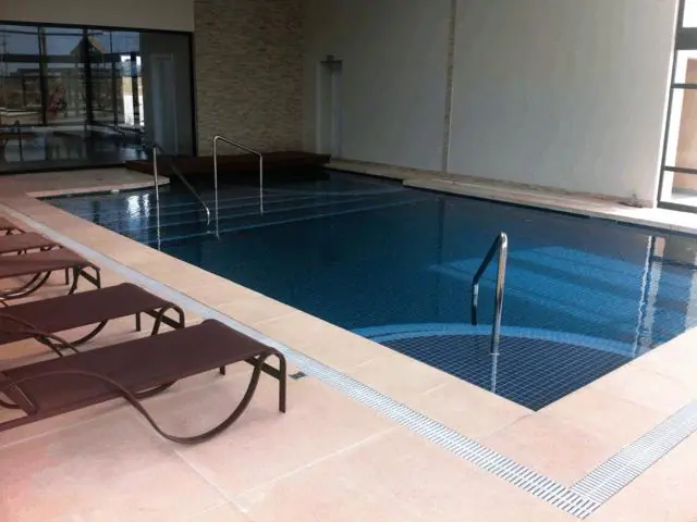 Piscina coberta com borda em piso cimentício